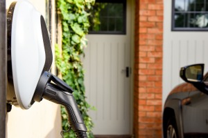 Electric car plugged in to charge outside home with power cable